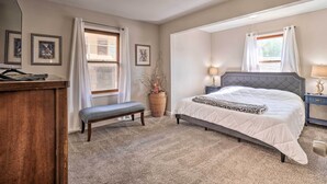 A bedroom with a bed, bench, bedside tables, and a window with curtains. - Rockaway Beach House w/ Fire Pit & River View! (Rockaway Beach)