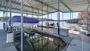Une zone abritée avec un quai, un bateau, des sièges et une vue sur l’eau et les collines.