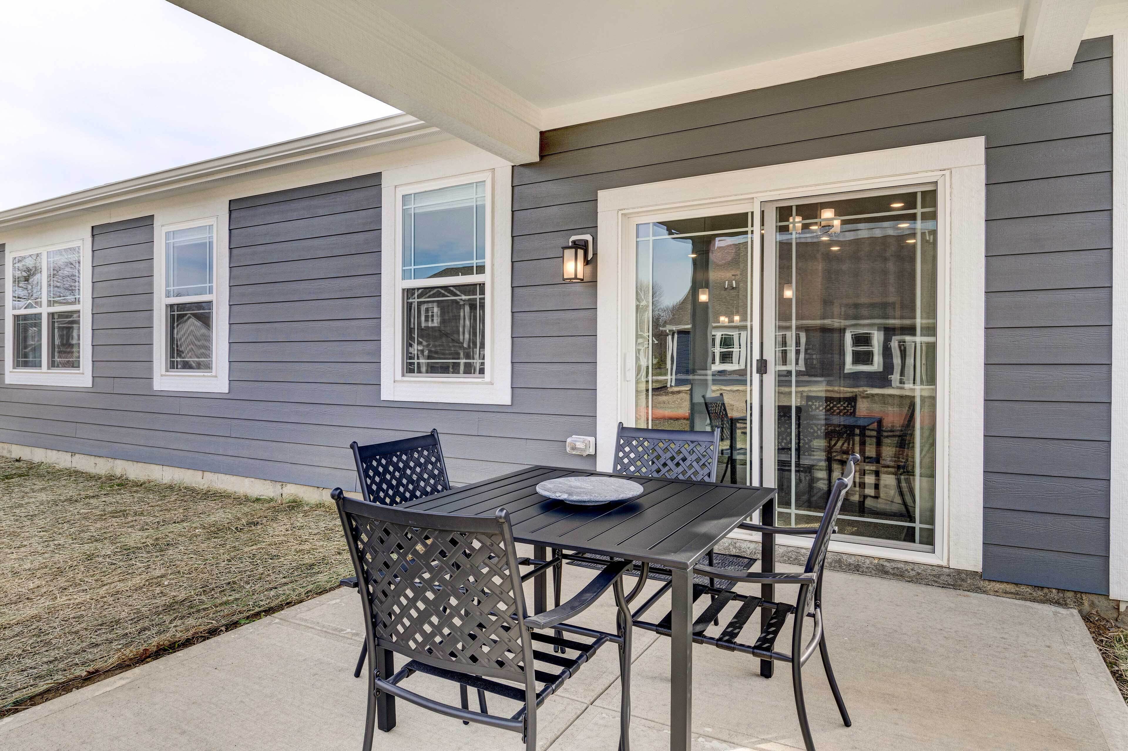 An outdoor patio with a table and chairs, a glass door entrance, and a small outdoor seating area.