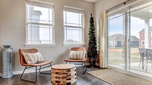 A spacious room with two wooden chairs, a round wooden ottoman, and a Christmas tree. - Spacious Home w/ Patio Near Fishers! (Fortville)