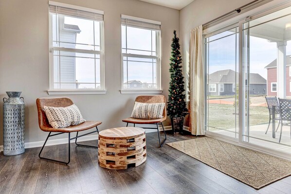 A spacious room with two wooden chairs, a round wooden ottoman, and a Christmas tree. - Spacious Home w/ Patio Near Fishers! (Fortville)