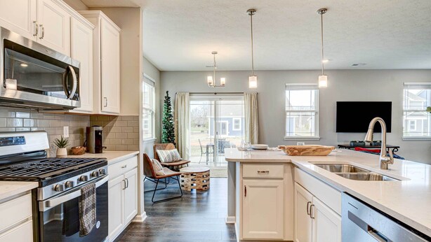 A modern kitchen with white cabinetry, a stainless steel stove, and a large island with a sink. - Spacious Home w/ Patio Near Fishers! (Fortville)