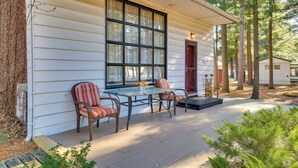 A wooden deck with a glass table and wicker chairs, surrounded by trees. - Wisconsin Cabin w/ ATV Trails, Near Lake Arbutus! (Merrillan)