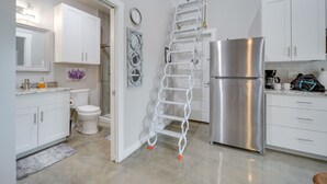 A modern kitchen with white cabinets, a stainless steel refrigerator, and a white ladder.