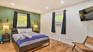 A modern bedroom with a bed, bedside tables, a TV, and a window with curtains.