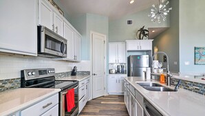 A modern kitchen with white cabinets, stainless steel appliances, and a wooden floor. - Private Beach + Oceanfront Balcony: Freeport Home (Freeport)
