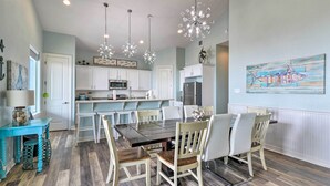 A modern kitchen with white cabinets, a dining table with chairs, and pendant lights. - Private Beach + Oceanfront Balcony: Freeport Home (Freeport)
