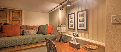 A cozy room with a sofa, a wooden table, a lamp, and framed pictures on the wall.