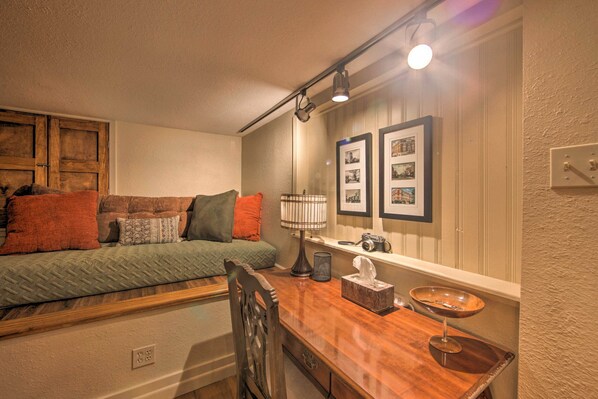 A cozy room with a sofa, a wooden table, a lamp, and framed pictures on the wall.