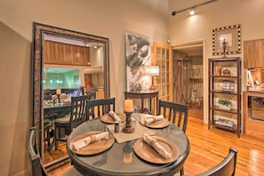 A dining area with a round glass table, wooden chairs, and a large mirror.