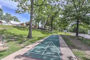 A shuffleboard court with a green surface, surrounded by trees and a grassy area. - Near Branson Landing / Sister Condo Very Close By! (Branson)
