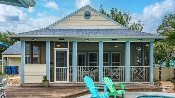 Un espacio al aire libre techado con piscina, muelle de madera y dos sillas Adirondack.