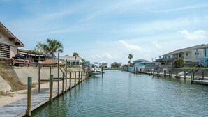 A canal with a wooden dock, houses on both sides, and a boat docked in the water. - Pelican Cove by Miss Kitty’s (Rockport)