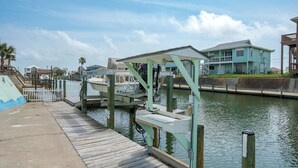 A dock with a boat, a wooden pier, and a house by the water. - Pelican Cove by Miss Kitty’s (Rockport)