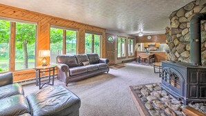 A cozy living room with a stone fireplace, leather furniture, and large windows offering a view of the outdoors. - 'mimis Place' ~ Ohio Countryside Duplex w/ Deck (Dalton)
