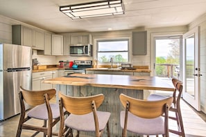 A modern kitchen with a large island, stainless steel appliances, and wooden chairs.