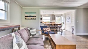 A modern living room with a sofa, a wooden coffee table, and a dining area with a bar stool and chairs. - Amenity-packed Nebo Oasis w/ Deck & Mtn Views (Nebo)
