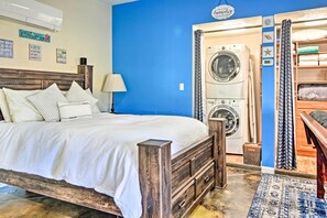 A bedroom with a wooden bed, a washing machine, and a laundry area. - Albuquerque Studio With Shared Pool & Fire Pit! (Albuquerque)