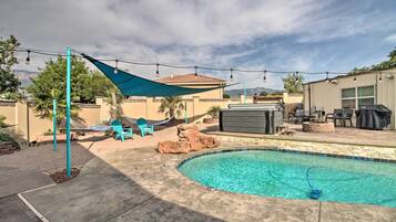 A backyard with a swimming pool, a hammock, and outdoor furniture.