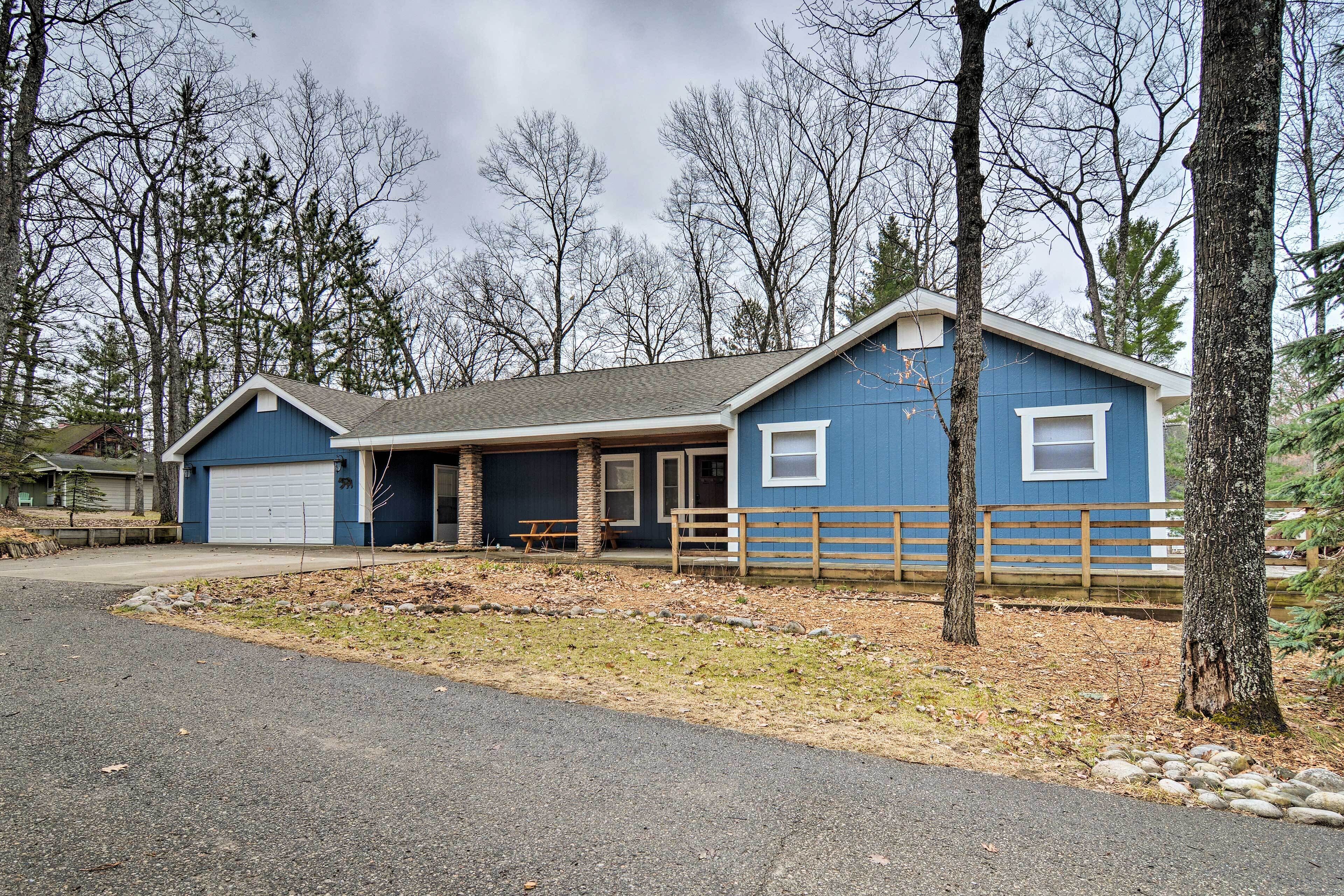 A two-story blue house with a garage, a covered porch, and a wooden fence.