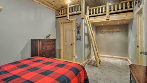 A bedroom with a bunk bed, wooden ceiling, a dresser, and a door. - Big Bear Lake All-season Northern Michigan Getaway (Johannesburg)