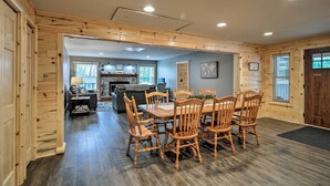 A spacious dining area with a wooden table and chairs, a fireplace, and a view of the outdoors. - Big Bear Lake All-season Northern Michigan Getaway (Johannesburg)