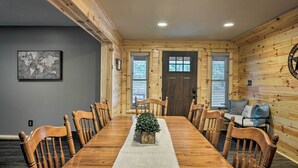 A wooden dining room with a long table, chairs, a small plant centerpiece, and a world map on the wall. - Big Bear Lake All-season Northern Michigan Getaway (Johannesburg)