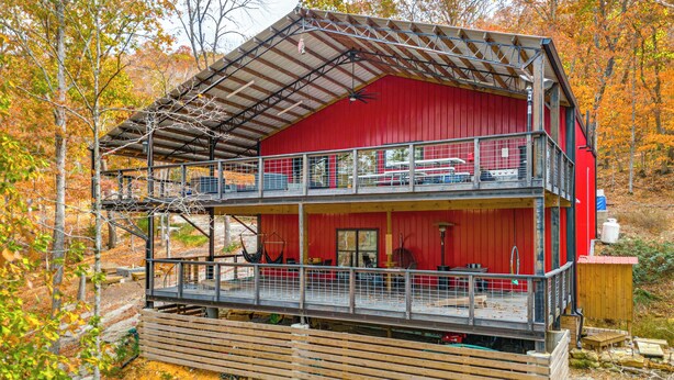 Une cabane rouge à deux étages, dotée d’un balcon au niveau supérieur, et entourée du feuillage automnal.