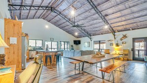 Une cuisine spacieuse dotée d’un grand îlot central, de bancs en bois et d’un plafond haut avec des poutres apparentes.