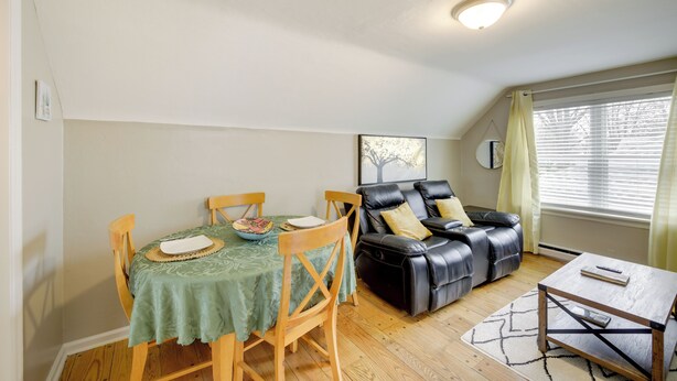 A dining area with a table set for two, a leather sofa, and a small coffee table. - Beech Grove Vacation Rental w/ Private Yard (Beech Grove)