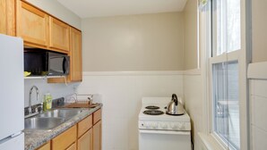 A kitchen with wooden cabinets, a stainless steel sink, a white stove, and a microwave. - Beech Grove Vacation Rental w/ Private Yard (Beech Grove)