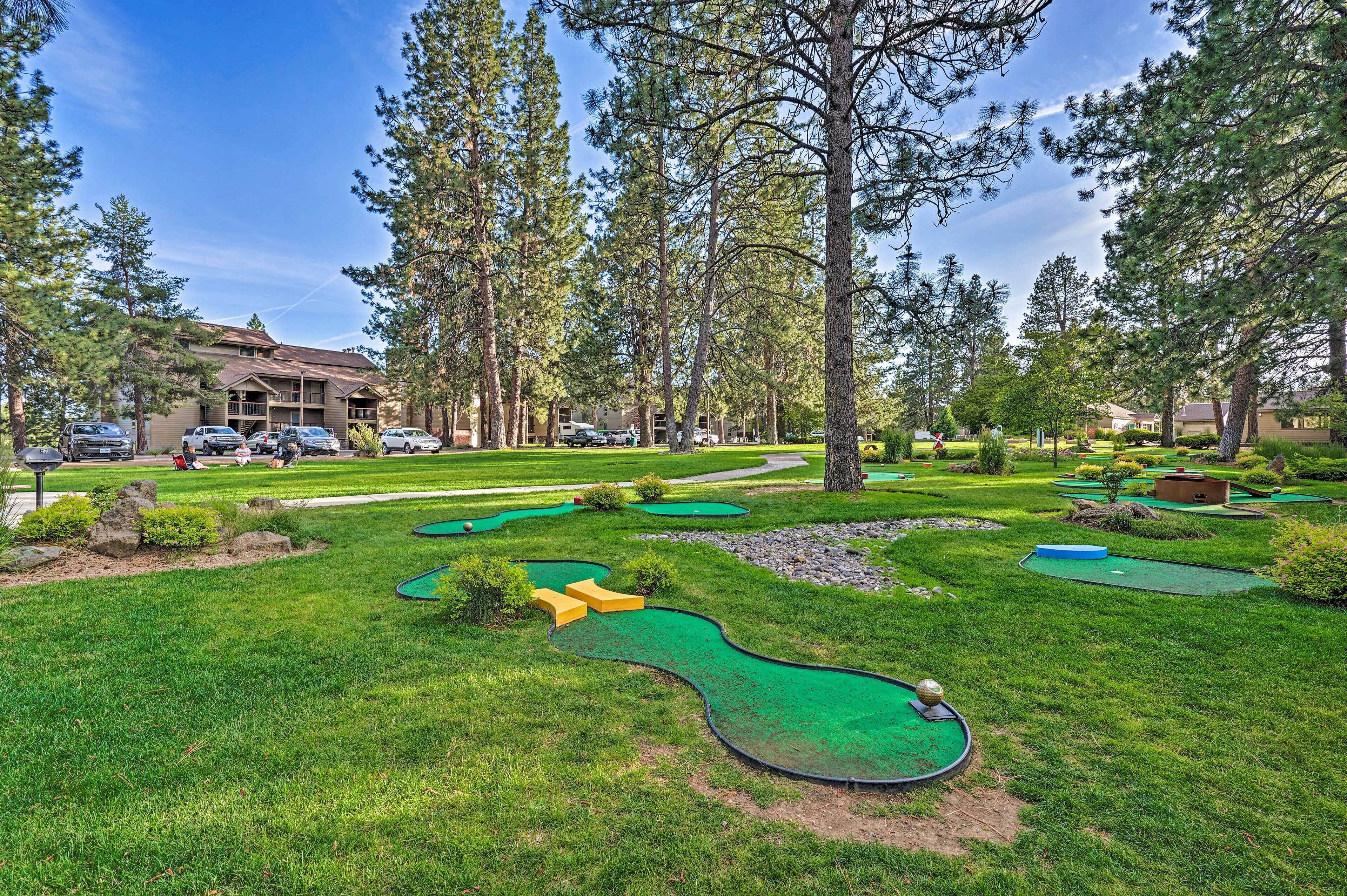 Un parcours de golf avec de nombreuses pelouses verdoyantes, des arbres et un bâtiment en arrière-plan.