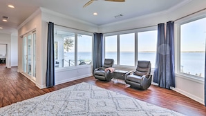 A spacious room with a large window overlooking a body of water, a ceiling fan, and two leather recliners. - Beautiful Waterfront Getaway w/ Dock! (Abbeville)