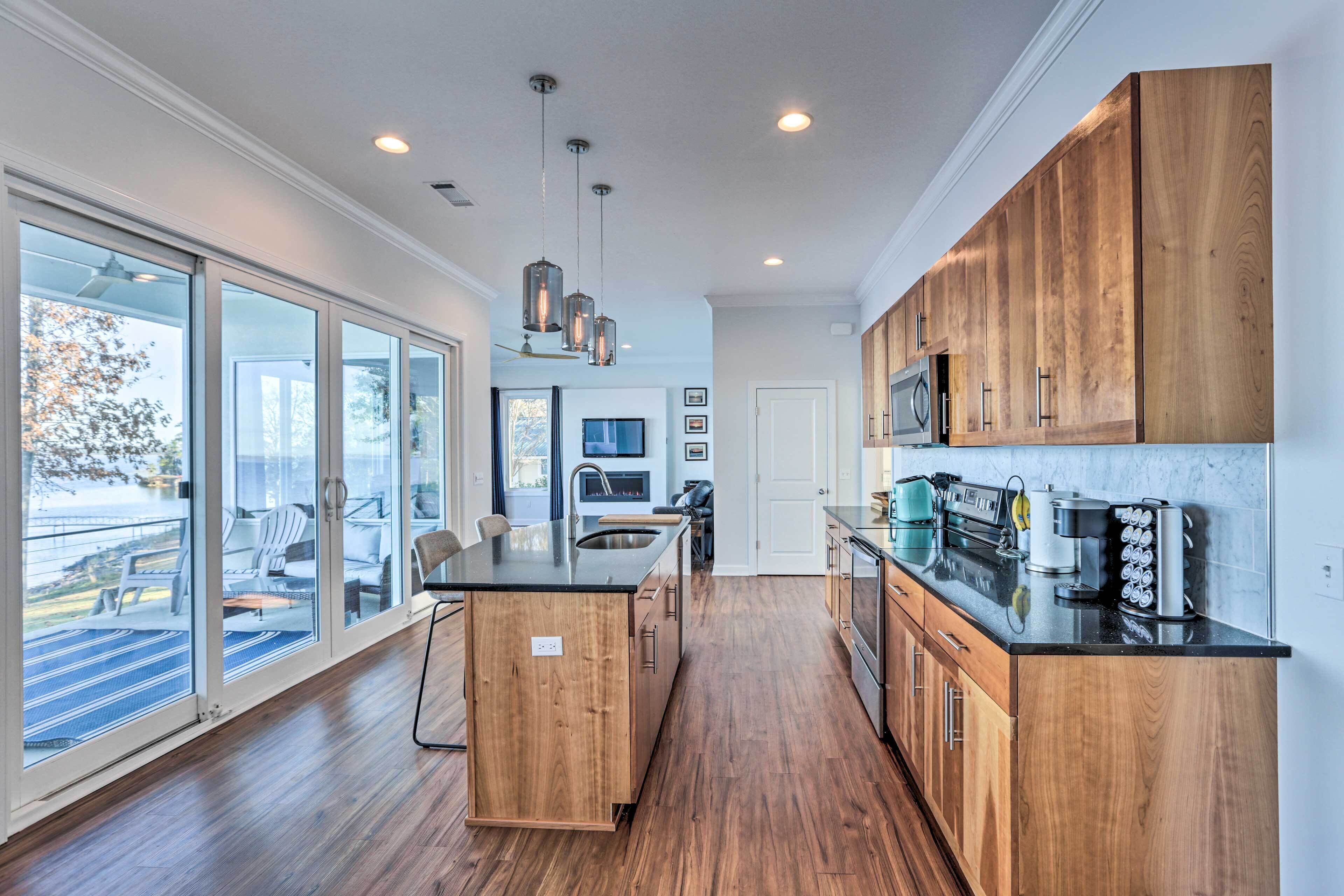 A modern kitchen with wooden cabinets, a black countertop, and a large island.