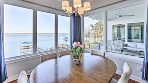 A dining area with a view of the sea, a chandelier, and a table with chairs. - Beautiful Waterfront Getaway w/ Dock! (Abbeville)