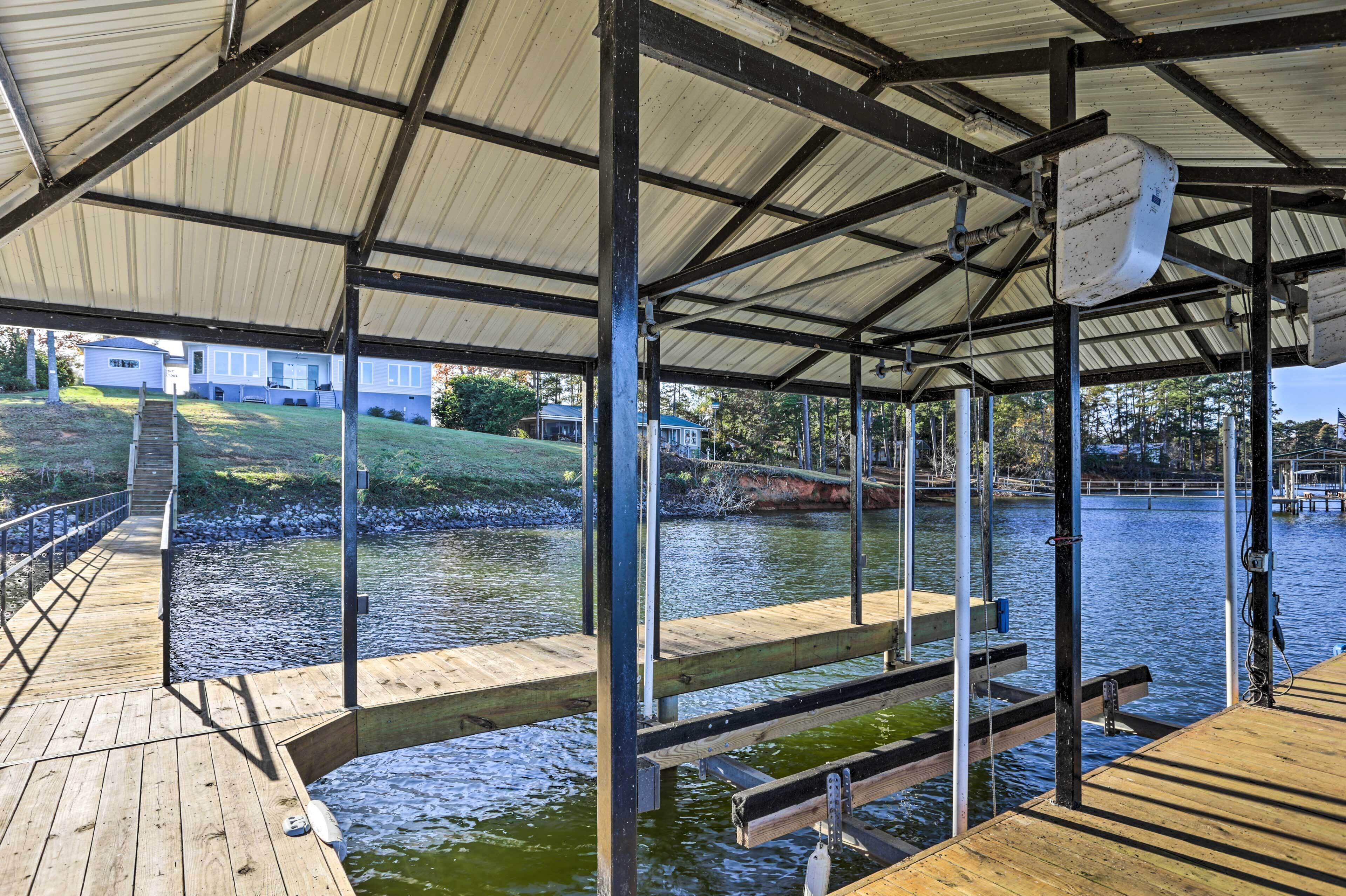 Une jetée abritée, avec une passerelle en bois menant à une zone herbeuse et une maison en arrière-plan.