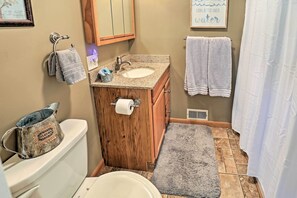 Features a sink, toilet, and shower area, with a comfortable rug on the floor.