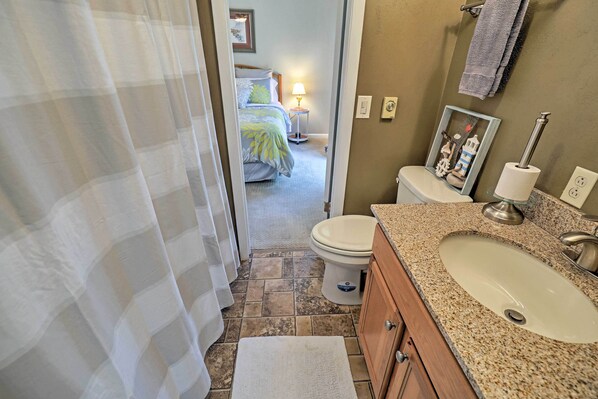 Bathroom features a granite countertop, white sink, and a toilet with a paper towel holder.