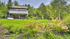 A two-story house with a garage, surrounded by a well-maintained lawn and flowering plants. - Auburn Vacation Rental Home Near Owasco Lake! (Auburn)