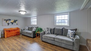 A living room with two grey sofas, a wooden chest of drawers, and a world map on the wall. - Bluefield Home w/ Covered Deck - Near Parks! (Bluefield)