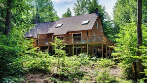 A wooden cabin with a balcony, surrounded by dense forest. - Bartlett Vacation Rental w/ Wraparound Deck! (Bartlett)