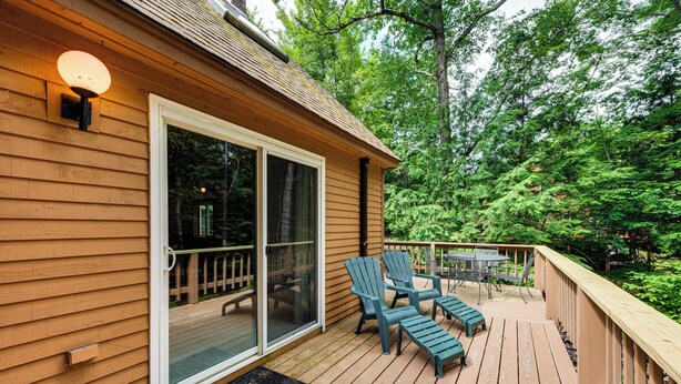 A wooden deck with a sliding glass door, outdoor furniture, and a view of a forested area. - Bartlett Vacation Rental w/ Wraparound Deck! (Bartlett)