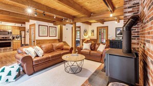 A cozy living room with leather sofas, a round coffee table, and a wood-burning stove. - Bartlett Vacation Rental w/ Wraparound Deck! (Bartlett)