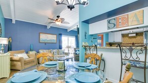 A dining area with a glass table set for four, blue plates, and a ceiling fan.