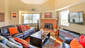 A living room with a fireplace, leather sofa, and a television. - Borrego Springs Condo w/ Private Hot Tub & Views! (Borrego Springs)