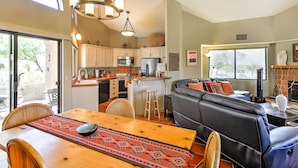 A modern kitchen with white cabinets, a central island, and a dining area with a wooden table and chairs. - Borrego Springs Condo w/ Private Hot Tub & Views! (Borrego Springs)