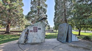 A park with a stone monument featuring a bird sculpture and a plaque, surrounded by trees and a paved walkway. - Boho-chic Folsom Retreat: Walkable Location! (Folsom)