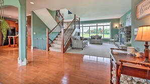 A spacious living area with a wooden staircase, a fireplace, and a view of the outdoors. - Blue Birds Perch: Stunning Home on Private Hilltop (Shipshewana)