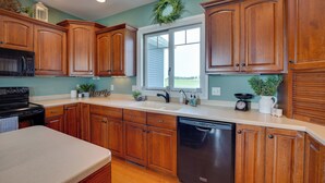 A kitchen with wooden cabinets, a dishwasher, a microwave, and a window with a view. - Blue Birds Perch: Stunning Home on Private Hilltop (Shipshewana)