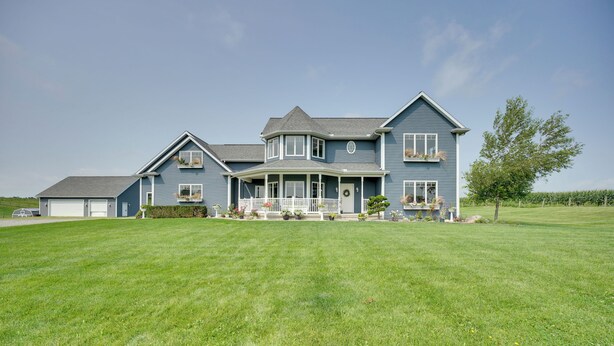 A large, two-story house with a wrap-around porch, multiple windows, and a well-maintained lawn. - Blue Birds Perch: Stunning Home on Private Hilltop (Shipshewana)